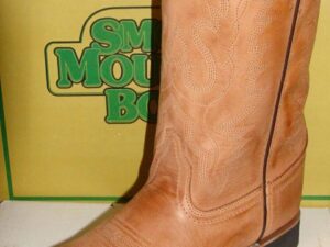 A tan cowboy boot in front of a box.