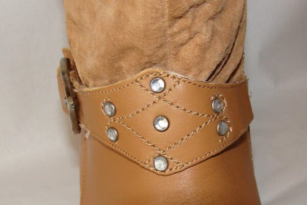 A close up of a tan boot with studded straps.
