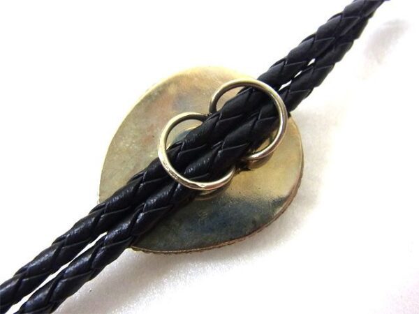 A black leather bracelet with a gold ring on it.