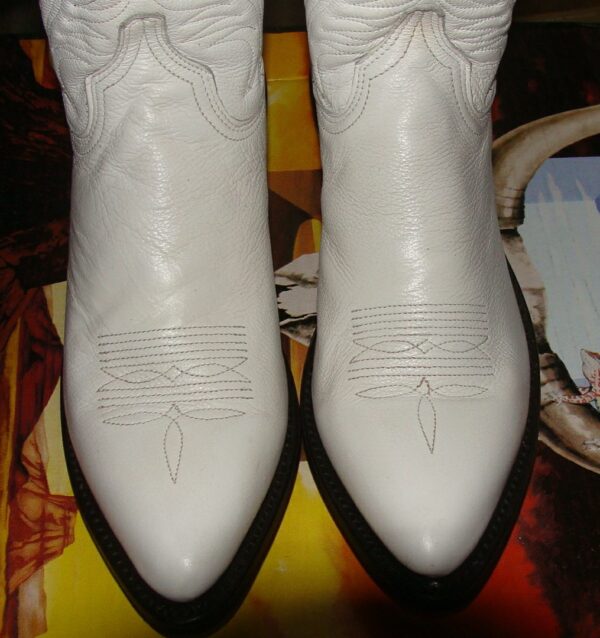A pair of Womens White Leather Cowboy Boots- USA made on a table.