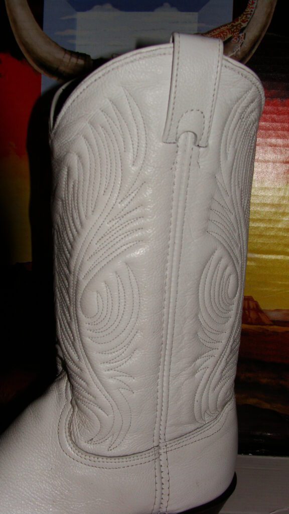 A pair of Womens White Leather Cowboy Boots- USA made on a table.