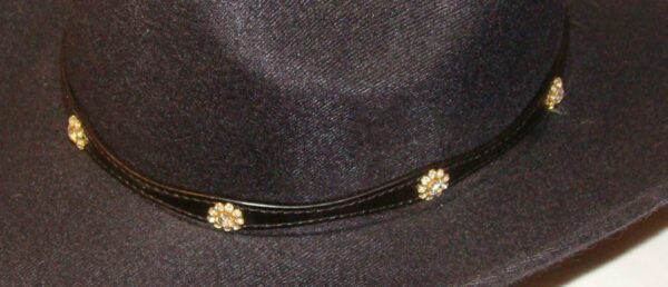 A black cowboy hat with gold accents and a Black leather WHITE Crystal Flower hat band with Silver buckle.