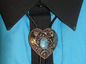 A Turquoise Stone Heart Shaped Silver Bolo Tie with a heart shaped brooch on it.