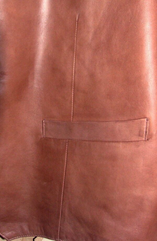 A Men's Scully Lambskin Leather Traditional Antique Western Vest hanging on a wall.