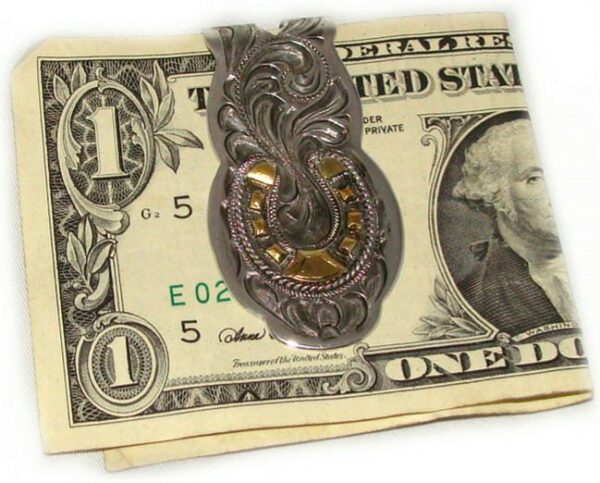 A Gold Horse Shoe money clip is sitting on top of a dollar bill.