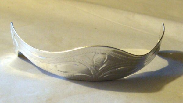 A silver cuff bracelet on a white surface with Medium- Laser Etched Silver Cowboy Boot Heel Guards.