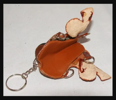 A Western Leather saddle keychain with a tan bird on it.