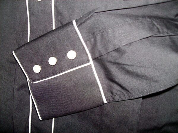 A close up of a Child vintage White piped Black western shirt with white buttons.