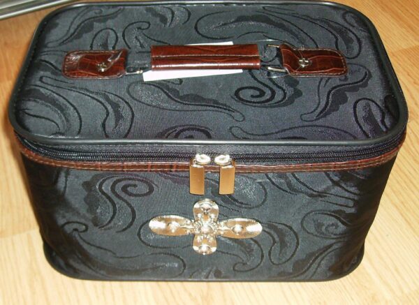 A 19" Black & brown croc print leather rolling carry on luggage with a cross on it sits on a wooden floor.
