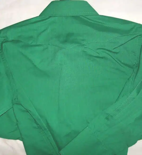 A green shirt is laying on a bed.