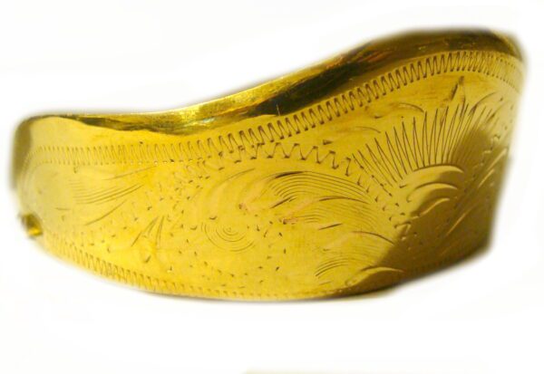 A gold cuff bracelet with a design on it.