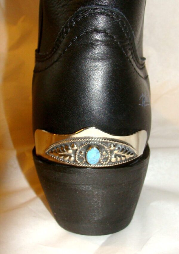 A close up of a black boot with a turquoise stone.
