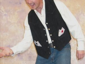 A man in a vest and jeans is posing for a picture.