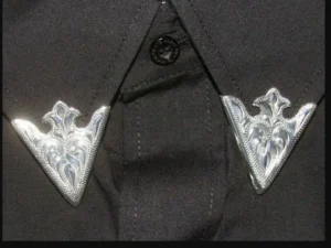 A close up of a black shirt with "Austin" Engraved silver collar tips.
