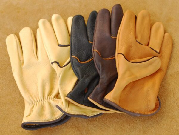 Four different colored leather gloves on a brown surface.