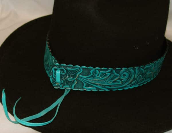 A 1.5" Tooled leather Turquoise Teal Cowboy Hat Band with a ribbon on it.