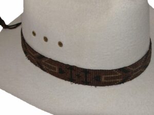 A white cowboy hat with a Brown Arrowhead beaded horse hair tassel hat band.