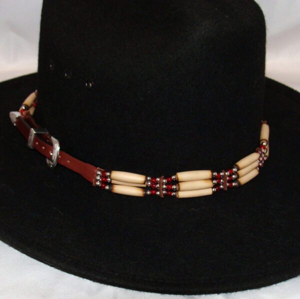 A black cowboy hat with a Cow Bone and Brown Leather Silver Buckle hat band.