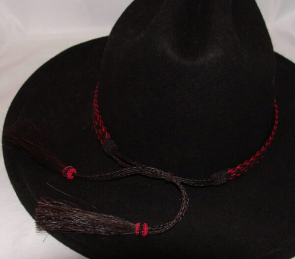 A USA MADE 1/2" Black & Hot Pink 3 Strand Horse Hair Hat Band with a red tassel on it.