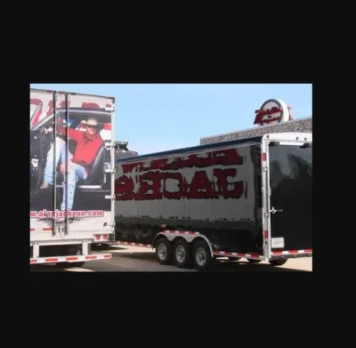 Two trailers parked in a parking lot, one with an Alan Jackson "Good Time" Mens Red western shirt by Scully hanging inside.