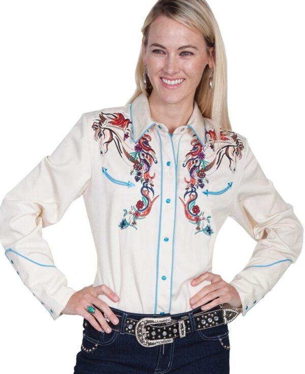 A woman in a Scully womens colorful horse embroidered cream western shirt and jeans is posing for a picture.