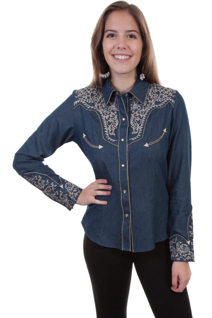 A woman smiling with her hand on her hip wearing the Scully Women's Scroll Embroidered Denim Western Shirt.