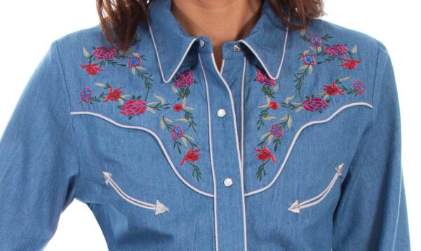 A woman wearing a Scully Womens Summer Floral Lightweight Blue Denim Western Shirt with embroidered flowers.