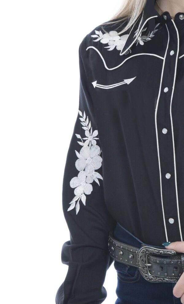 A woman wearing a Womens Scully White Periwinkle Black Western Shirt with embroidered flowers.