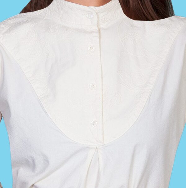 A woman is wearing a Ladies Scully Embroidered Bib front Ivory 1800's Blouse.