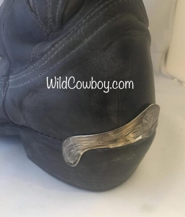 A pair of black cowboy boots with Laser Etched Antique Silver Cowboy Boot Heel Guards.