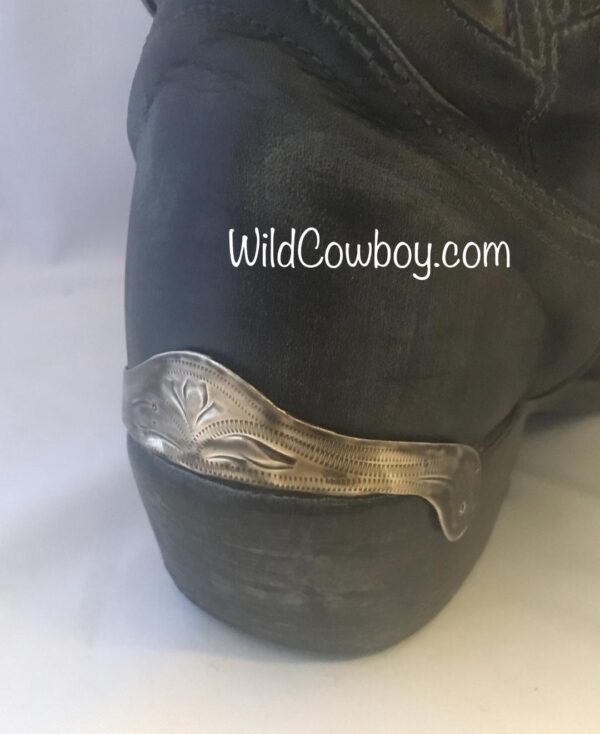A pair of black cowboy boots with silver buckle and Laser Etched Antique Silver Cowboy Boot Heel Guards.