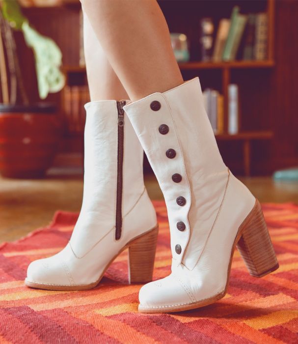 A woman wearing Amelia Off White Leather Button Snap Womens Zip Granny Boots on a rug.