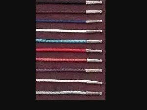 A row of USA MADE Leatherette Bolo Tie Strings, Cords - Pick Colors on a black background.