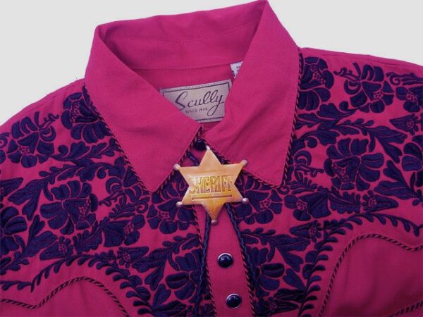 A pink and black cowboy shirt with a star on it was replaced by the Gold Sheriff Badge Bolo Tie.