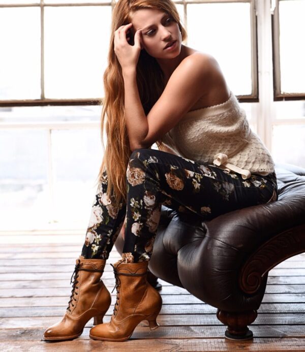 A young woman sitting on Eleanor Tan White Leather Womens Granny Boots.