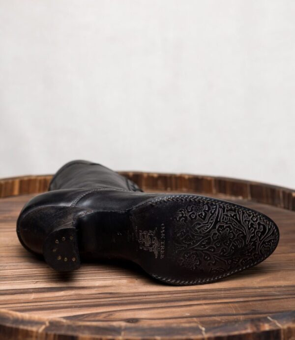 A pair of Eleanor Black Leather Womens Granny Boots on top of a wooden table.