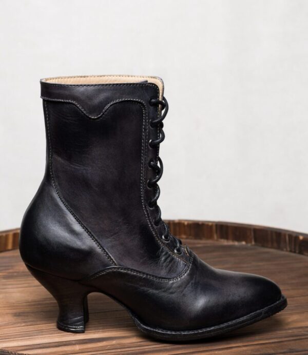 A pair of Eleanor Black Leather Womens Granny Boots on top of a wooden barrel.