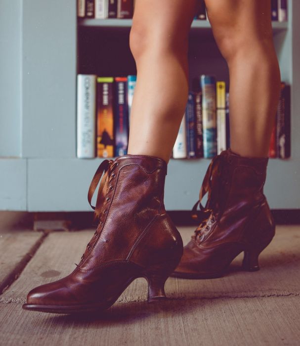 A woman wearing Elizabeth Teak Leather Womens Granny Boots in front of a bookcase.