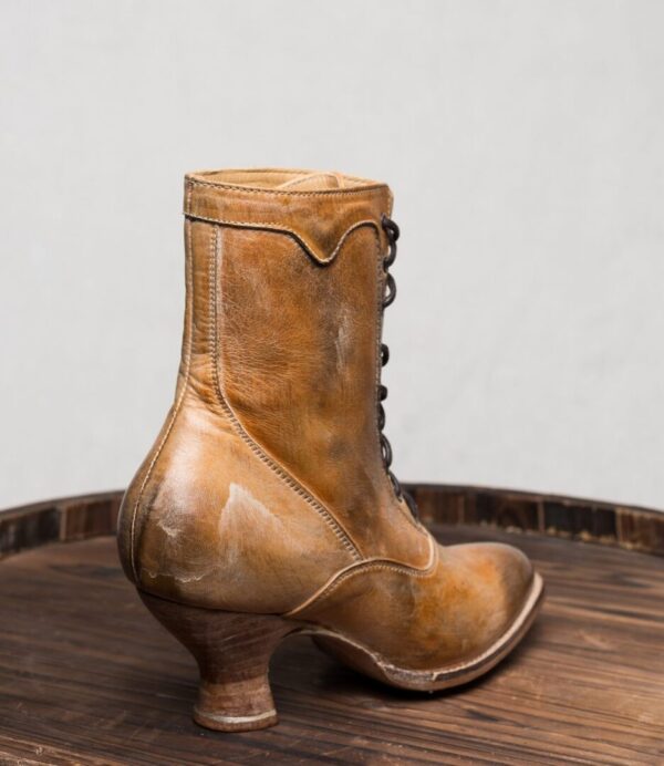 A pair of Eleanor Tan White Leather Womens Granny Boots atop a wooden barrel.