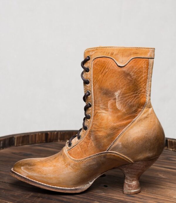 A pair of Eleanor Tan White Leather Womens Granny Boots on top of a wooden barrel.