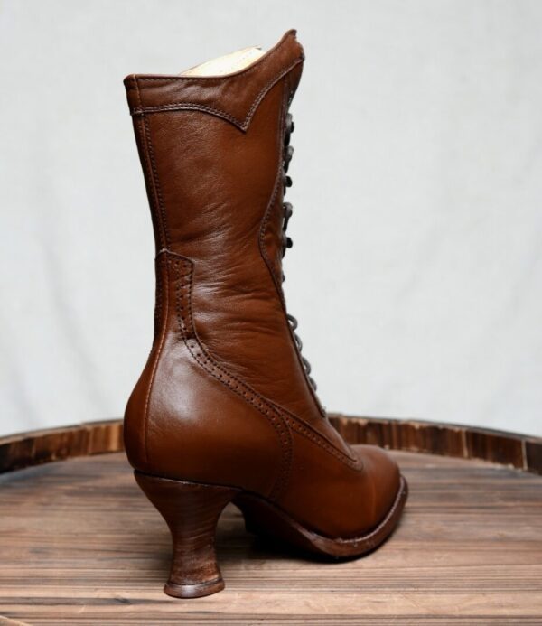 A pair of Jasmine Cognac Kidskin Womens Granny Boots on top of a wooden barrel.