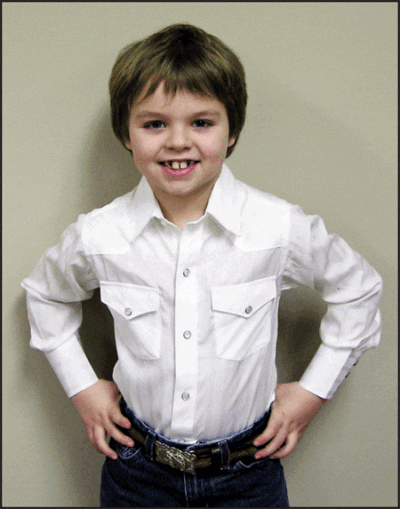 A young boy wearing a child white tone on tone western shirt and jeans.