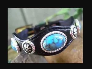 A Silver Concho Black Leather Turquoise Bracelet USA with turquoise stones.