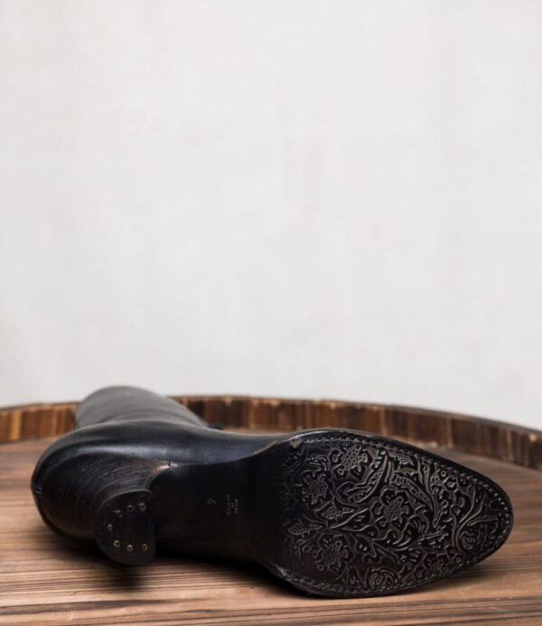 A pair of Mirabelle Black Leather Womens Granny Boots on top of a wooden table.