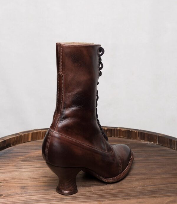 A pair of Mirabelle Teak Leather Women's Granny Boots on top of a wooden barrel.