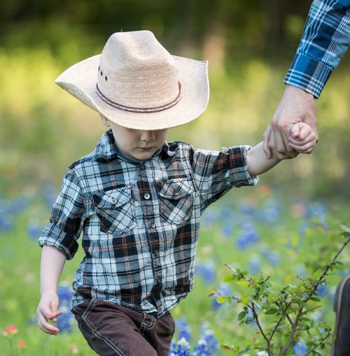 Father holding son wearing cowboy hat