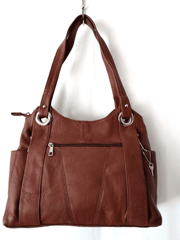 A "Diane" Women's Black Leather Concealed Carry Handbag w/ Holster hanging on a wall.