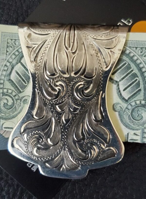 A Silver Scroll Engraved Curved Western Money Clip sitting on top of a credit card.